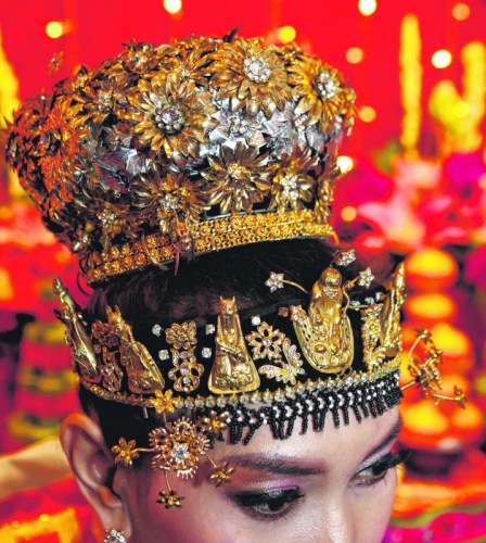 土生華人新娘頭戴裝飾珠寶的鳳冠，特別之處是額前飾以八仙形象的金頭套與花形鑲鉆金飾。 (新加坡《聯(lián)合早報(bào)》/梁麒麟 攝)