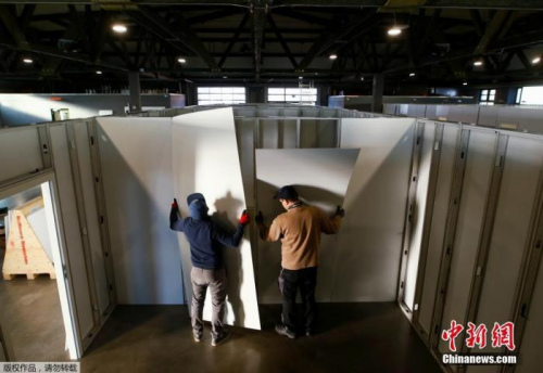 當(dāng)?shù)貢r(shí)間3月25日，德國(guó)希勒斯海姆，工作人員和志愿者將市政大廳改建為醫(yī)療中心用于收治新型冠狀病毒患者。圖為工作人員和志愿者在安裝醫(yī)療中心隔間的墻面。