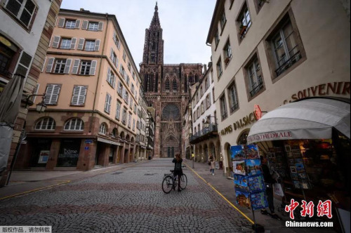 資料圖：法國“封城”生效前，斯特拉斯堡大教堂附近，一名婦女在街上騎自行車。