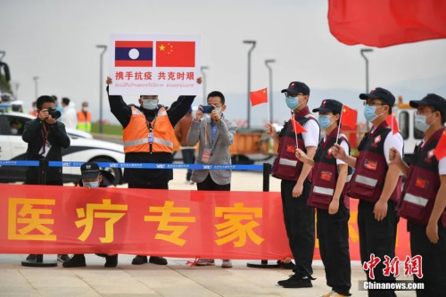 抗疫醫(yī)療專家組一行12人順利完成工作任務(wù)，乘包機(jī)平安飛抵云南昆明。圖為機(jī)場工作人員手舉印有中老兩國國旗的牌子迎接專家組。( <a target='_blank' >中新社</a>記者 劉冉陽 攝)