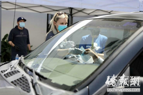 夢想中心的義工在給低收入者發(fā)放口罩。(美國《僑報》/邱晨 攝)