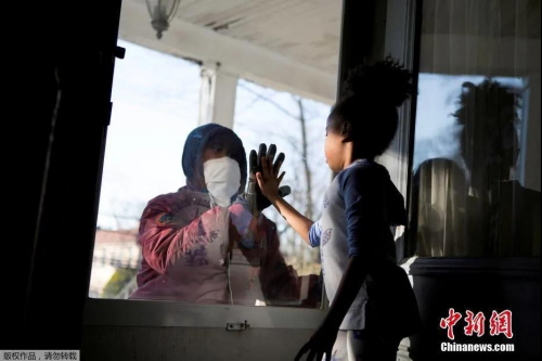 當(dāng)?shù)貢r(shí)間4月11日，美國(guó)紐約州新冠疫情持續(xù)嚴(yán)峻，新羅謝爾市的醫(yī)療行業(yè)從業(yè)人員哈希姆在工作期間與家人保持“社交距離”，和女兒隔門(mén)相會(huì)擊掌。