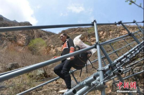 　5月13日，四川省涼山州昭覺縣支爾莫鄉(xiāng)阿土列爾村31戶村民帶著行李通過鋼梯下山，集中搬遷至昭覺縣易地扶貧搬遷縣城集中安置點(diǎn)的新家。張浪 攝