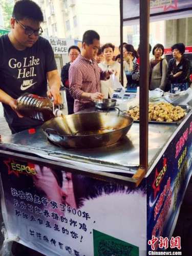 郭方正(左)正在往鍋里倒炸雞用的油，攤位邊等待的顧客已排起長(zhǎng)隊(duì)?！〔苠P 攝