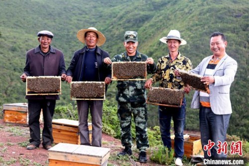 布哈與村民展示養(yǎng)蜂成果。圖片由武警部隊提供