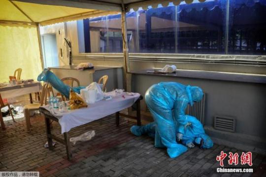 資料圖：印度新德里的核酸監(jiān)測點，一名衛(wèi)生工作者因疲勞過度倒下。Manish Swarup