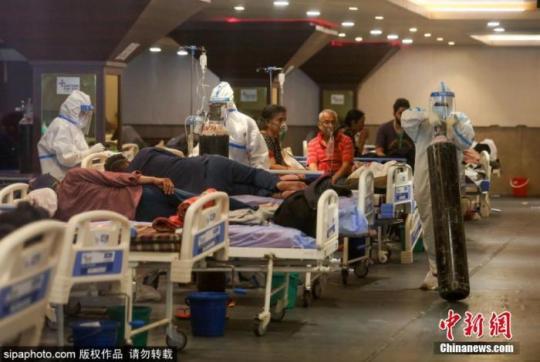 連續(xù)激增的確診病例，導(dǎo)致印度多地醫(yī)療系統(tǒng)癱瘓，許多患者只能在臨時(shí)搭建的場(chǎng)所接受治療。圖為醫(yī)護(hù)人員在運(yùn)送氧氣罐。