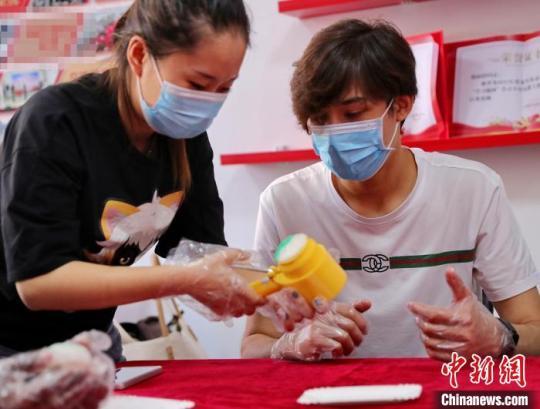 圖為社區(qū)居民和外國(guó)留學(xué)生一起制作月餅。　曹建雄 攝