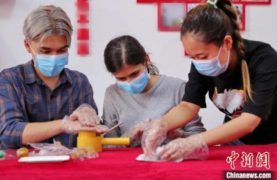 圖為社區(qū)居民和外國(guó)留學(xué)生一起制作月餅?！〔芙ㄐ?攝