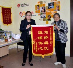僑眷吳玉英(右)向工作人員贈(zèng)送錦旗