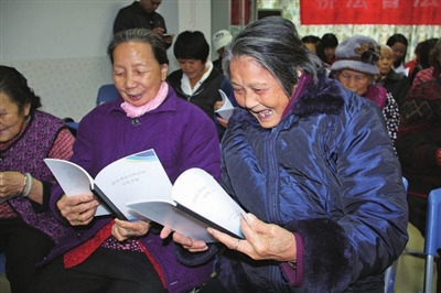 中國僑網(wǎng)大鵬新區(qū)居民開心翻看僑法宣傳手冊。(《深圳僑報》/林琳 攝)