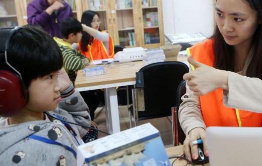 中國僑網圖為聽障兒童正在“試用”。