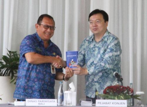 中國僑網(wǎng)駐登巴薩總領(lǐng)館代總領(lǐng)事陳巍向巴厘省旅游局長贈送手冊。