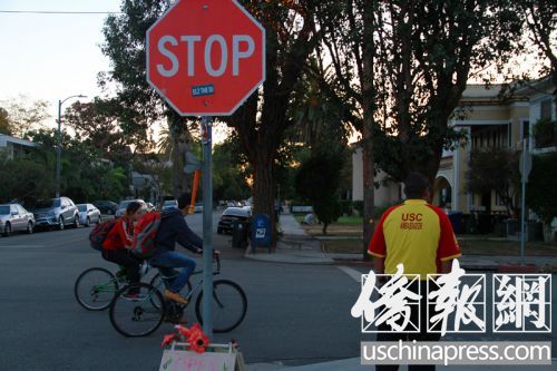 2名中國留學(xué)生騎車在“小黃衣”旁邊經(jīng)過。(美國《僑報》/周慧一