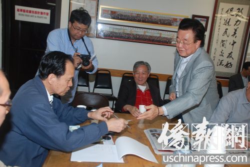 吳國(guó)寶向華商總會(huì)辦公室主任雷榮暢遞交其捐款支票。(美國(guó)《僑報(bào)》/吳卓明