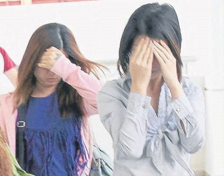 女被告李淑燕(前),雙手遮臉避開鏡頭。(馬來西亞《南洋商報》)