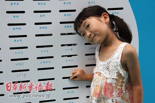 一名日本兒童正向?qū)懹凶约好值耐稁趴诶锓湃?00日元。(日本新華僑報(bào)網(wǎng))