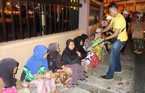 洪英發(fā)的員工派發(fā)白米給長者。(馬來西亞《星洲日?qǐng)?bào)》)