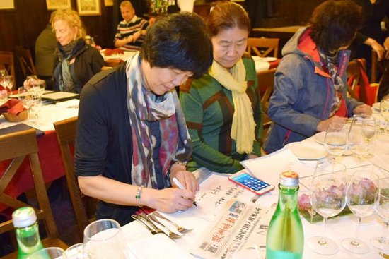 郎平為歐洲時(shí)報(bào)及海外華僑華人題寫(xiě)賀詞(右側(cè)為郎平的姐姐郎洪)。(法國(guó)《歐洲時(shí)報(bào)》/宣絢