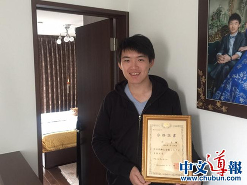 何彥徵手捧司法考試合格證書(日本《中文導(dǎo)報》)