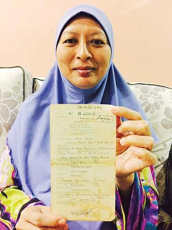 中國(guó)僑網(wǎng)教師莎麗達(dá)手持報(bào)生紙欲尋找親生父母。(馬來西亞《光華日?qǐng)?bào)》)