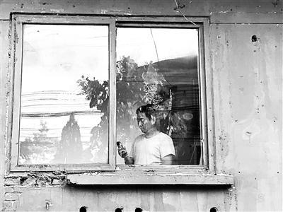 中國僑網(wǎng)章瑩穎的父親站在窗口翻著手機(jī),依然沒有女兒的消息 攝影/實(shí)習(xí)記者 張曜麟