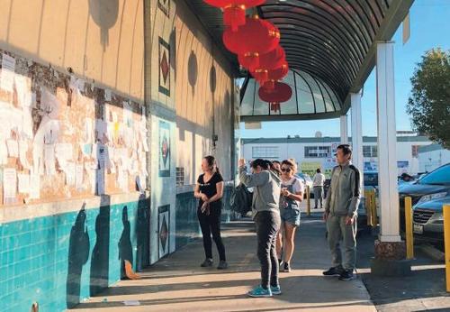 中國僑網(wǎng)洛杉磯夏威夷超市廣告欄前駐足觀看的華人。(美國《僑報》/聶達 攝)