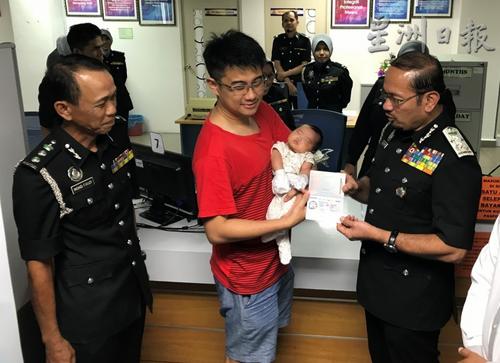 中國僑網(wǎng)慕斯達(dá)法(右)移交護(hù)照給民眾。(馬來西亞《星洲日報(bào)》)