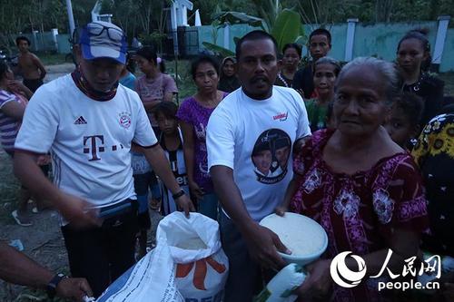 中國僑網(wǎng)接受中國志愿者救援物資的當(dāng)?shù)貫?zāi)民