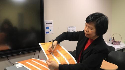 中國僑網(wǎng)美國芝加哥選舉委員會(huì)外展主任劉珍演示用紙投票的勾選方式。(美國《世界日?qǐng)?bào)》/董宇 攝)