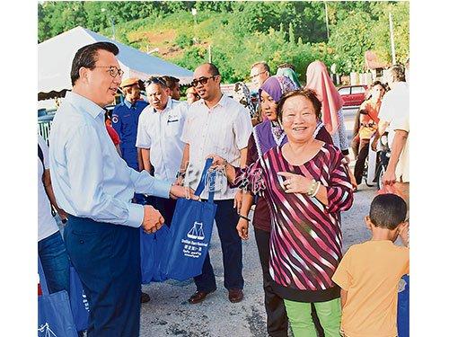 中國僑網(wǎng)廖中萊(左)派送開齋節(jié)禮袋,華裔市民也獲得。(馬來西亞《中國報》)