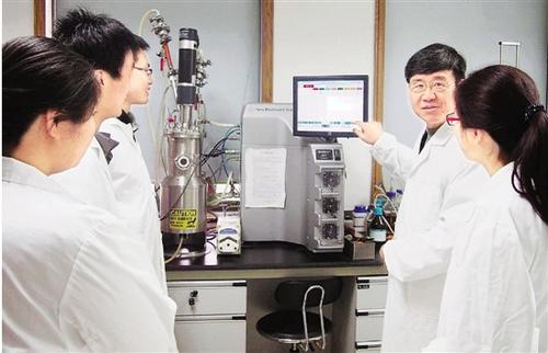 中國僑網(wǎng)王一成(右二)生前給省農(nóng)科院的學(xué)生講解發(fā)酵罐使用方法。