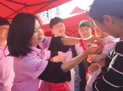 中國僑網志愿者為小女孩系上粉紅絲帶。 莊越 攝