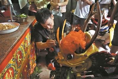 中國(guó)僑網(wǎng)梁漢勇穿著順德特色的香云紗在為龍舟“點(diǎn)睛”。