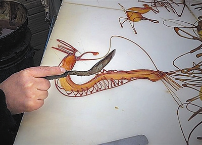 中國僑網龔保欣正在創(chuàng)作幽蘭糖畫。