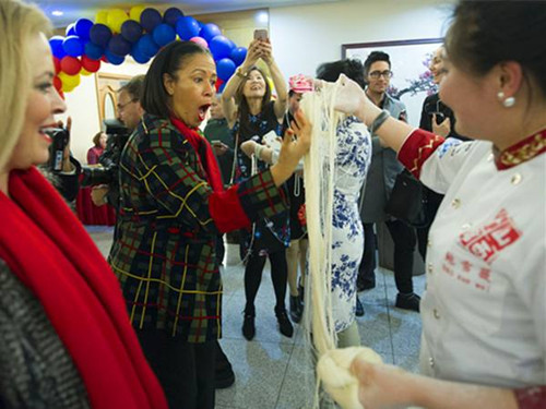 圖為洛杉磯市前禮賓局局長埃爾加·夏普(前左二)對鮑雪薇師傅制作的超細龍須拉面驚嘆不已。(楊磊