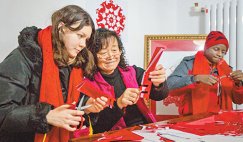 中國(guó)僑網(wǎng)外國(guó)留學(xué)生向當(dāng)?shù)胤沁z文化傳承人學(xué)習(xí)民間傳統(tǒng)剪紙。