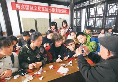 中國(guó)僑網(wǎng)圖為民間藝人講解剪紙技巧。 李文寶攝 (新華社發(fā))