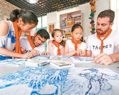 中國僑網圖為支教國際生在和學生學習版畫雕刻?! ∪嗣褚曈X