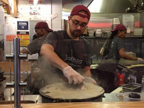 中國僑網(wǎng)尹奈格嫻熟地攤著煎餅。(美國《世界日報》/李碩 攝)