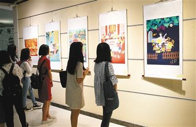 中國(guó)僑網(wǎng)農(nóng)民畫(huà)吸引大學(xué)生駐足觀看 記者 尚洪濤 攝