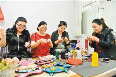 中國僑網(wǎng)武麥花(中)與繡娘一起繡制虎頭眼罩。 楊力 攝
