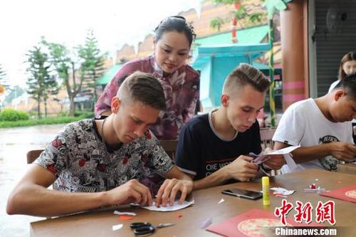 中國僑網(wǎng)饒寶蓮正在指導(dǎo)“洋徒弟”剪紙 李星凱 攝