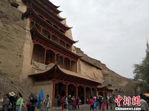 中國僑網(wǎng)圖為2019年3月,敦煌莫高窟九層樓前游人絡(luò)繹不絕。(資料圖) 馮志軍 攝