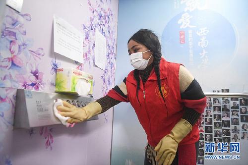 中國僑網(wǎng)西南大學(xué)尼日利亞籍留學(xué)生志愿者方雯對電梯按鈕進行衛(wèi)生消毒(新華網(wǎng)/王全超 攝)