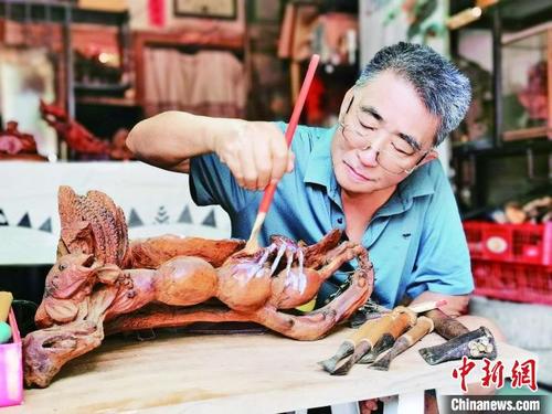 中國僑網(wǎng)廣州增城根雕非遺傳承人吳金石在創(chuàng)作中 增城區(qū)委宣傳部 供圖